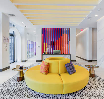 a large yellow sofa in the middle of a room with a black and white rug