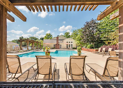 a swimming pool with chairs around it and a house in the background at Highland Ridge Apartments, Overland Park , KS 66210