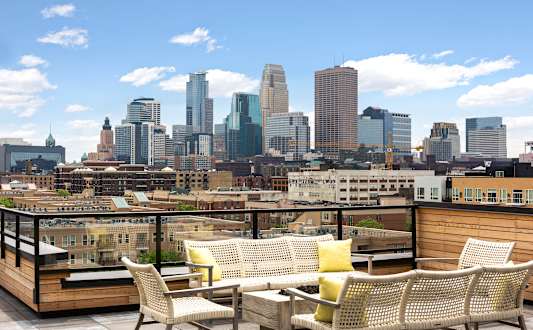 A patio with a table and chairs overlooking a city skyline.
