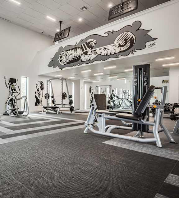 A gym with a variety of equipment including treadmills, weights, and exercise machines.