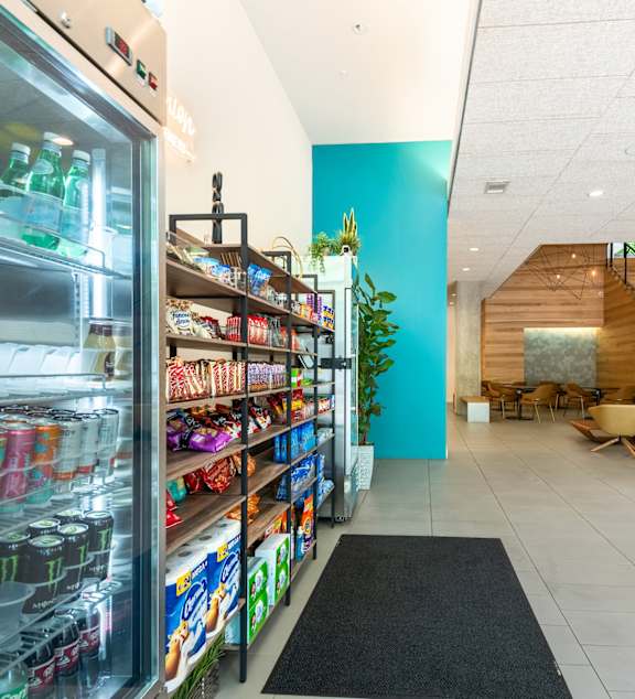 A frosty glass case filled with drinks sits next to a wall of shelves filled with snacks.