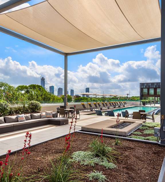 A rooftop patio with a pool and a view of the city.