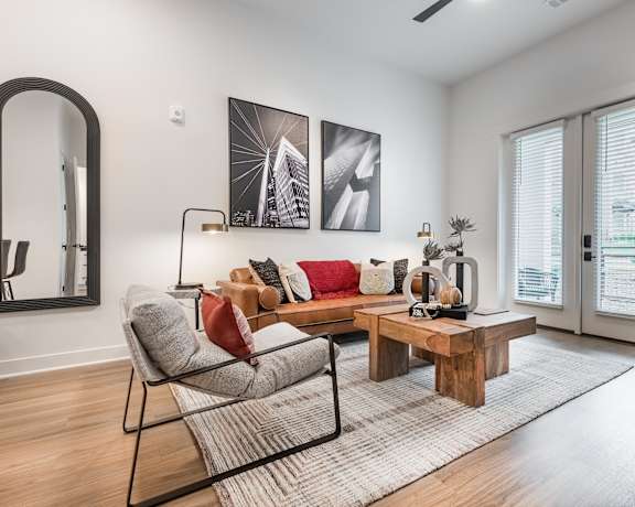 A living room with a grey sofa, a wooden coffee table, and a large mirror on the wall.