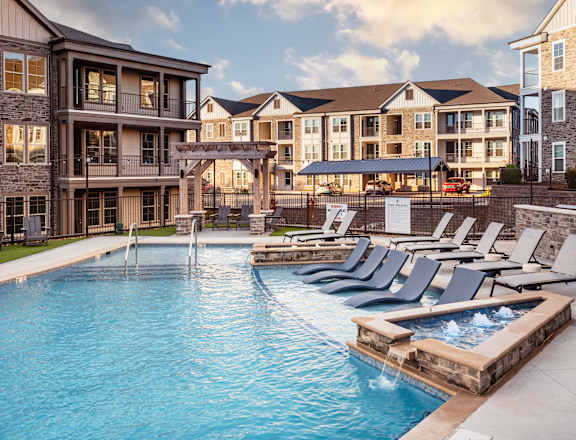 a swimming pool with lounge chairs in front of an apartment building