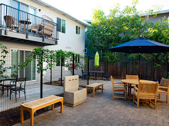 an outdoor patio with tables and chairs and an umbrella
