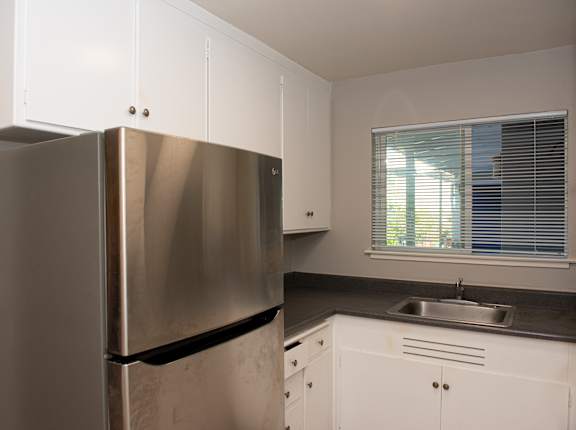 a kitchen with white cabinets and a stainless steel refrigerator