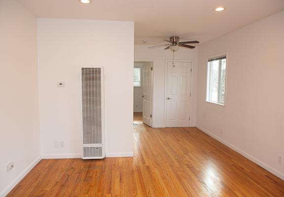A room with a wood floor and a ceiling fan.