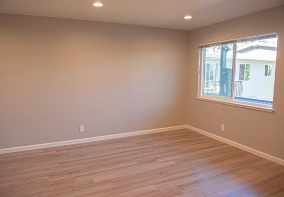 an empty living room with wooden floors and a window