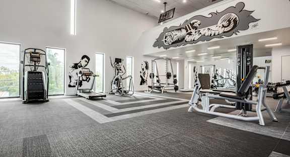 A gym with a variety of equipment including treadmills, weights, and exercise machines.