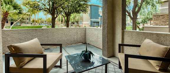 a patio with two chairs and a glass table