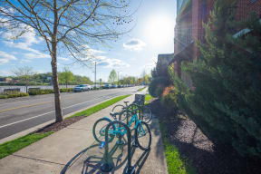a row of bikes parked on a sidewalk next to a street
