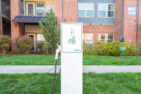 a white electric sign in the grass in front of a building