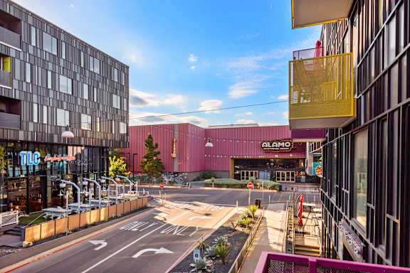 A street view of a city with a building that has a sign that reads "ALAMO".