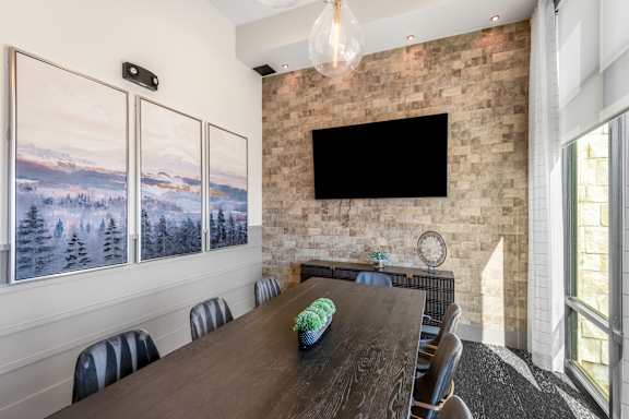 A conference room with a long table and chairs, a flat screen TV, and pictures on the wall.