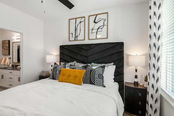 A bedroom with a large bed and two framed artworks on the wall.