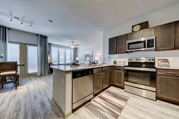 A modern kitchen with a stainless steel refrigerator and grey cabinets.