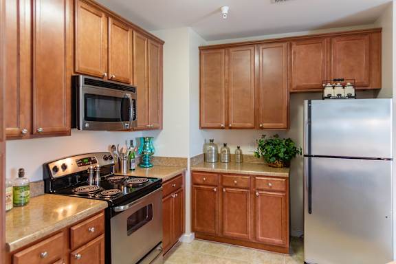 A kitchen with wooden cabinets and a stainless steel refrigerator.