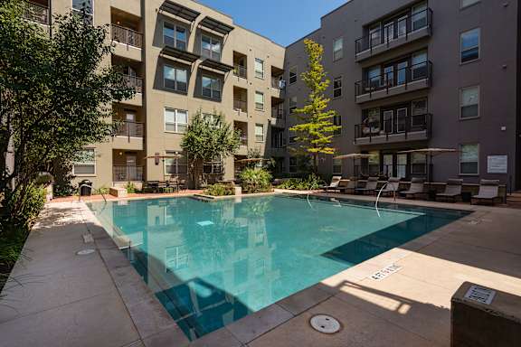 an apartment swimming pool in front of The Can Plant, San Antonio Luxury Apartments