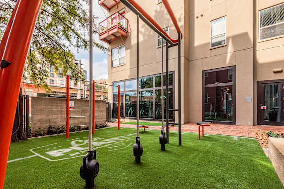 a courtyard with grass and a building with a playground and swings
