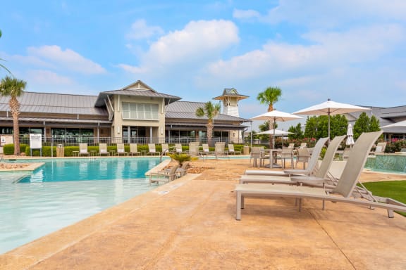 a resort style pool with lounge chairs and umbrellas