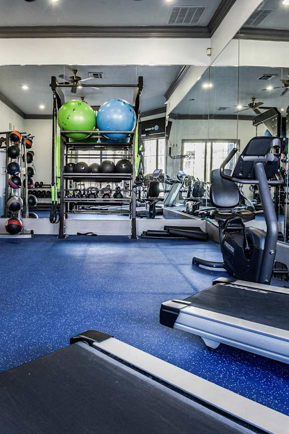 a gym with cardio machines and weights on the floor