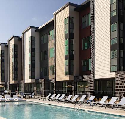 A row of modern apartment buildings with a pool in front.