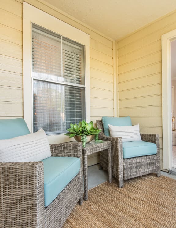 a porch with two wicker chairs and a table at Highland Ridge Apartments, Overland Park , KS 66210