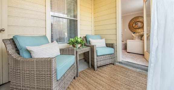 a porch with two wicker chairs and a table at Highland Ridge Apartments, Overland Park , KS 66210