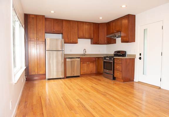 A kitchen with wooden cabinets and a stainless steel refrigerator.