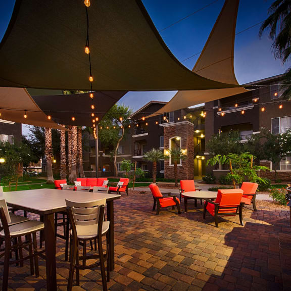 a patio with tables and chairs and umbrellas at night