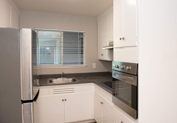 a kitchen with white cabinets and stainless steel appliances and a window
