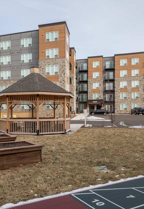 A gazebo sits in the middle of a playground surrounded by apartment buildings.