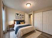 Thumbnail 4 of 8 - A bedroom with a bed, nightstand, and artwork on the wall.