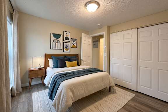 A bedroom with a bed, nightstand, and artwork on the wall.