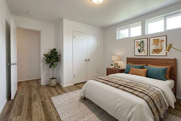 A bedroom with a bed, a plant, and a lamp.