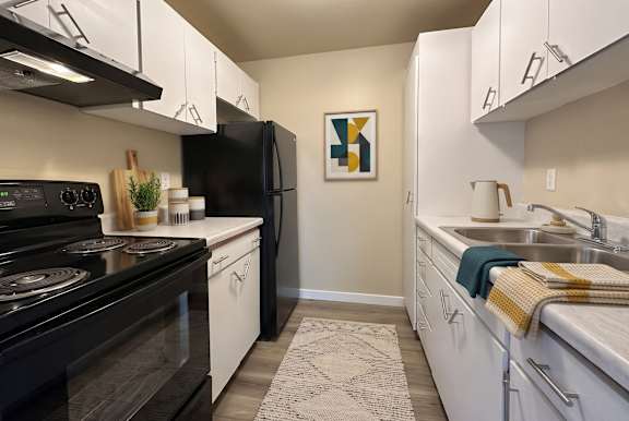 A kitchen with black and white appliances and a fridge with a picture hanging on the wall.