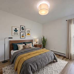 A living room with a grey couch, a white table, and a large window.