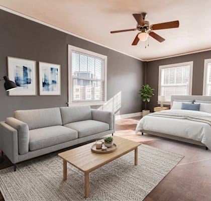 A bedroom with a large bed, a couch, a coffee table, and a ceiling fan.