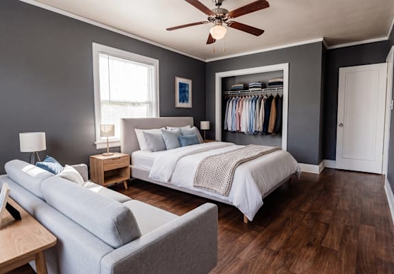 A bedroom with a bed, a couch, and a ceiling fan.
