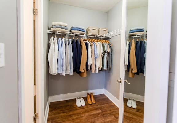 A white closet with clothes and shoes.