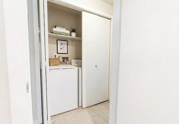 A small white refrigerator is in a narrow hallway.