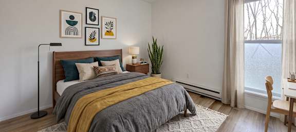 A bedroom with a bed, a chair, and a window.