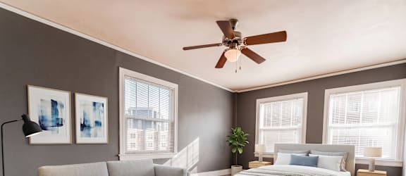 A bedroom with a large bed, a couch, a coffee table, and a ceiling fan.