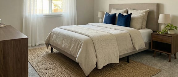 A bedroom with a large bed and a painting on the wall.