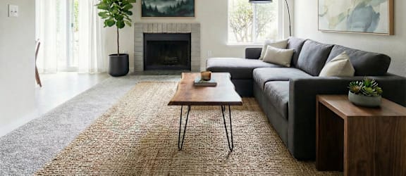 A living room with a black couch, a fireplace, and a painting on the wall.