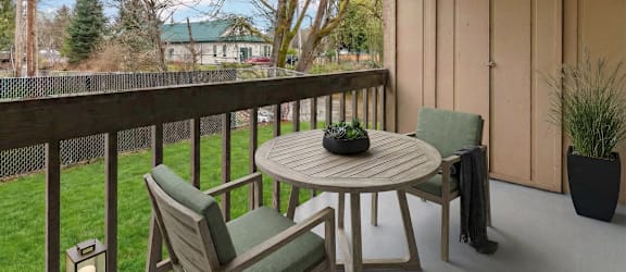 A wooden table with chairs on a patio with a view of a house and trees.