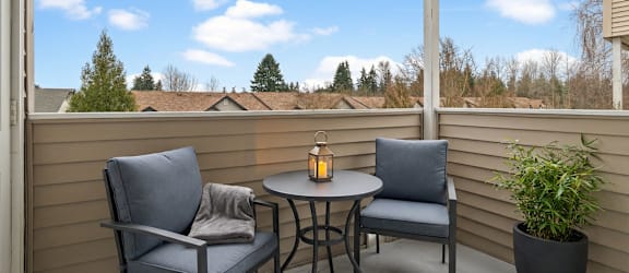 A patio with a table and two chairs and a potted plant.