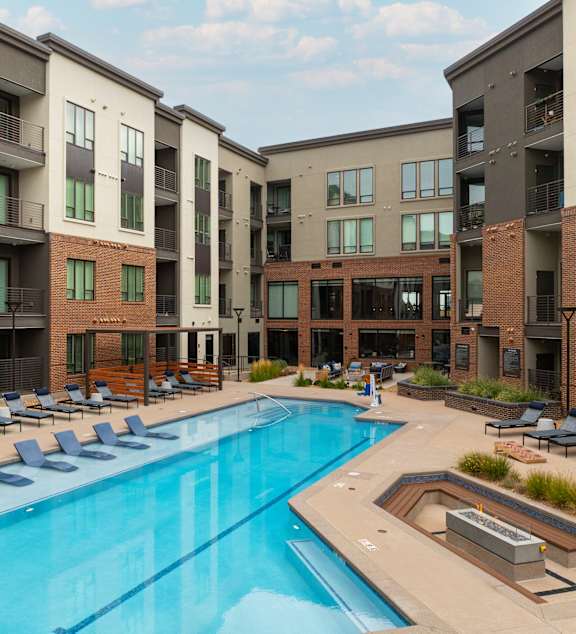 A swimming pool surrounded by lounge chairs and buildings.