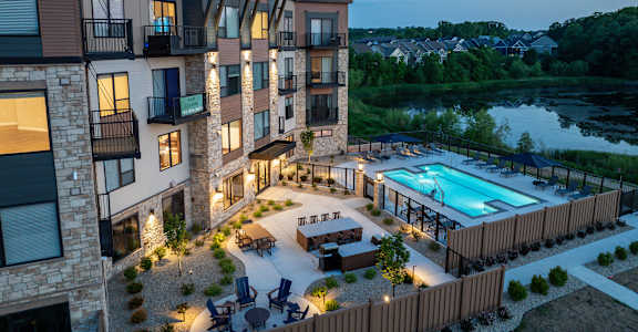 A modern apartment complex with a pool and outdoor seating area.
