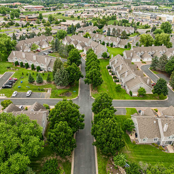 A residential street with houses on both sides and a car parked on the right. at Seasons Villas Apartments, Woodbury, MN